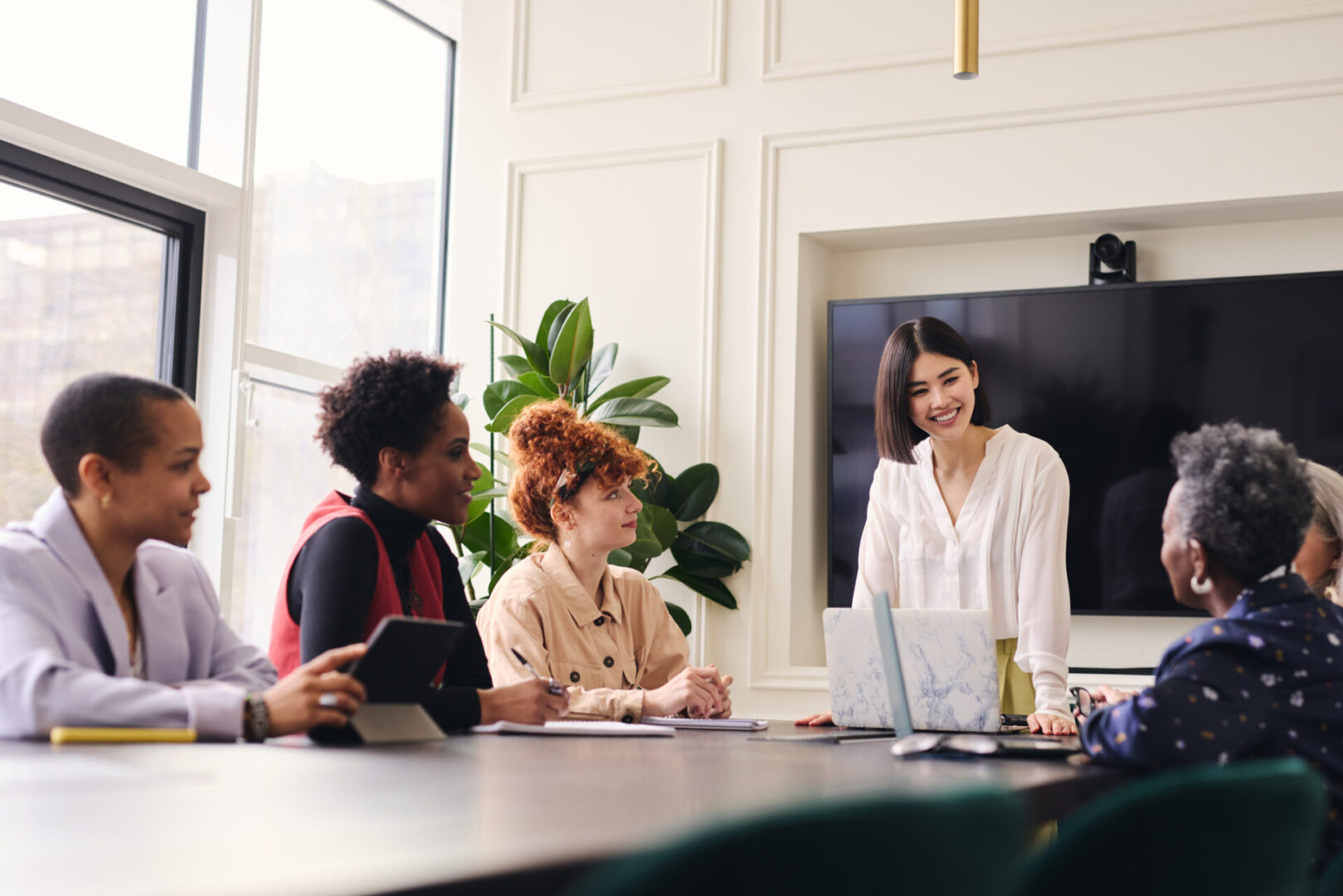 Mid adult Chinese woman in business meeting with multi ethnic colleagues Businesswomen meeting, collaborating on project.