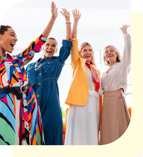 Four women joyfully raising their arms.